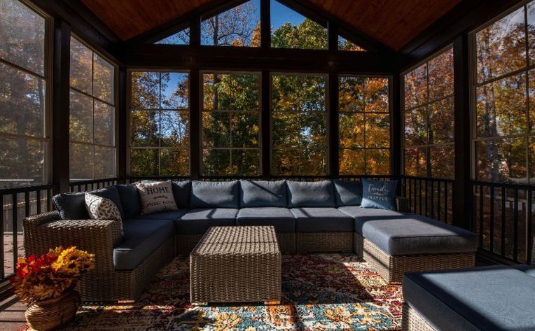 A sunroom in fall with a blue-cushioned grey sofa set and a centertable